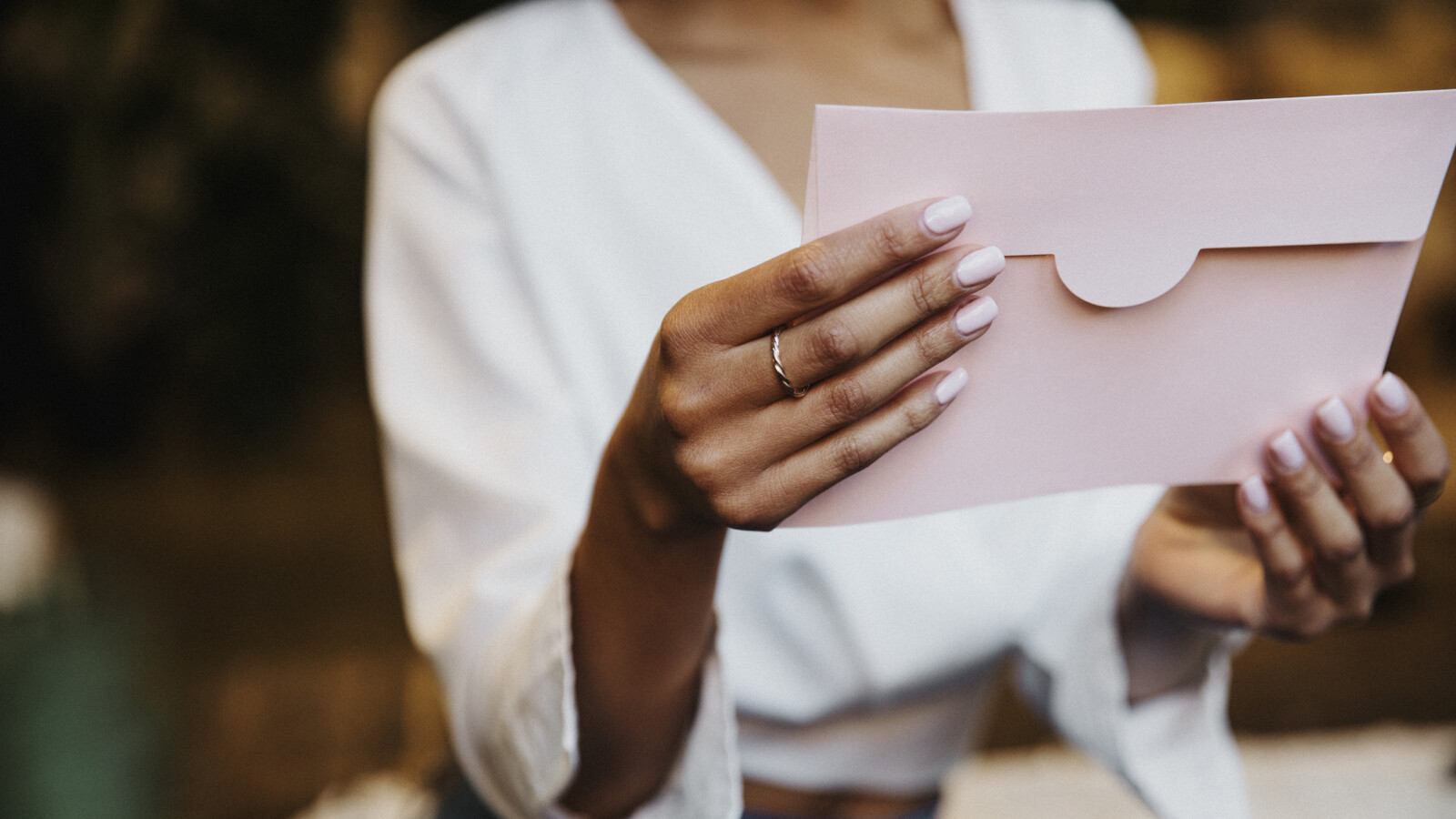 Eine Frau hält einen rosa Umschlag in den Händen.