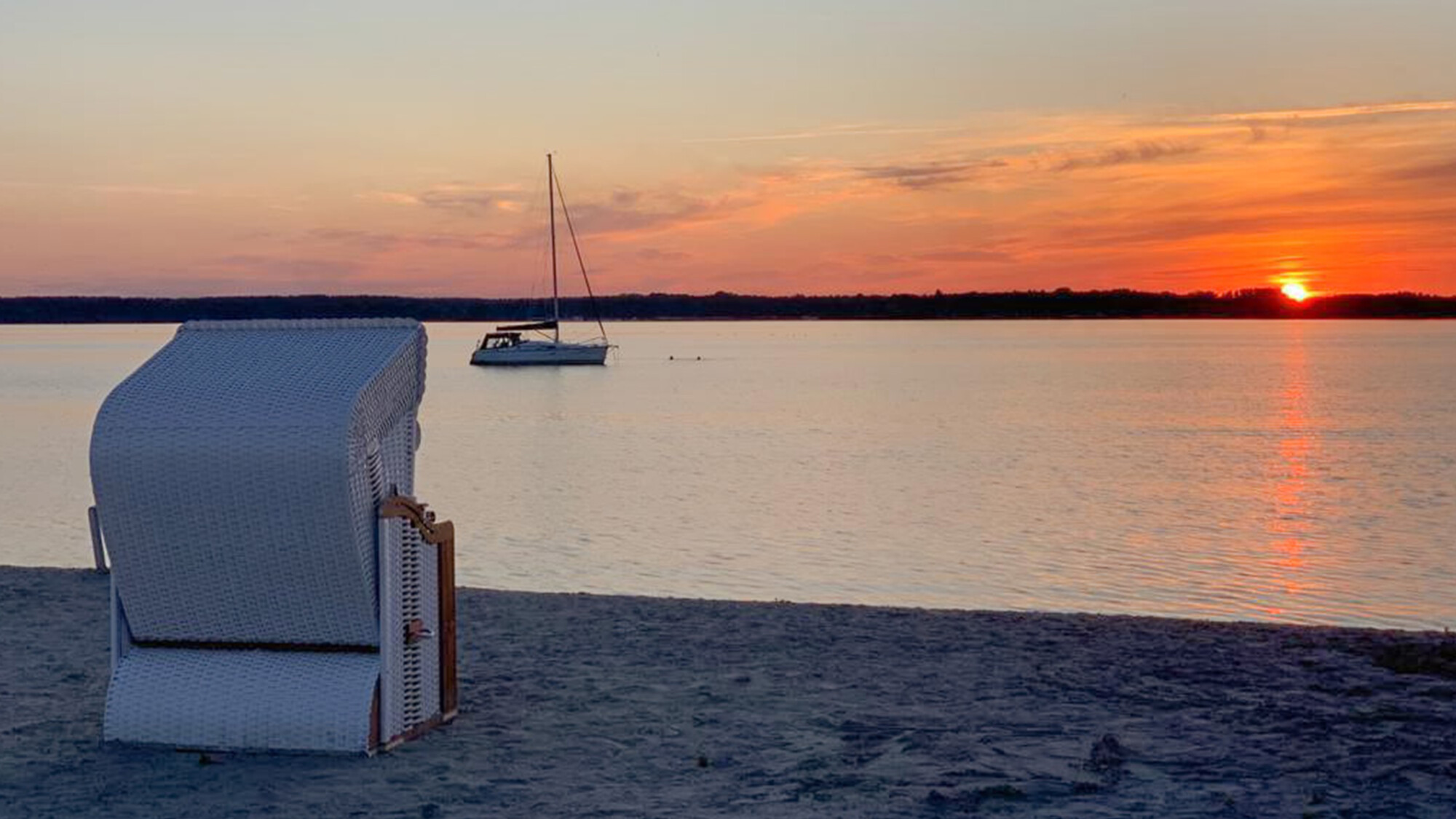 Ein Strandkorb im Sonnenuntergang am Strand des MareMüritz Yachthafen Resorts.
