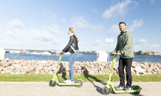 Paar fährt Roller auf einem Weg vor dem Yachthafen Resort.