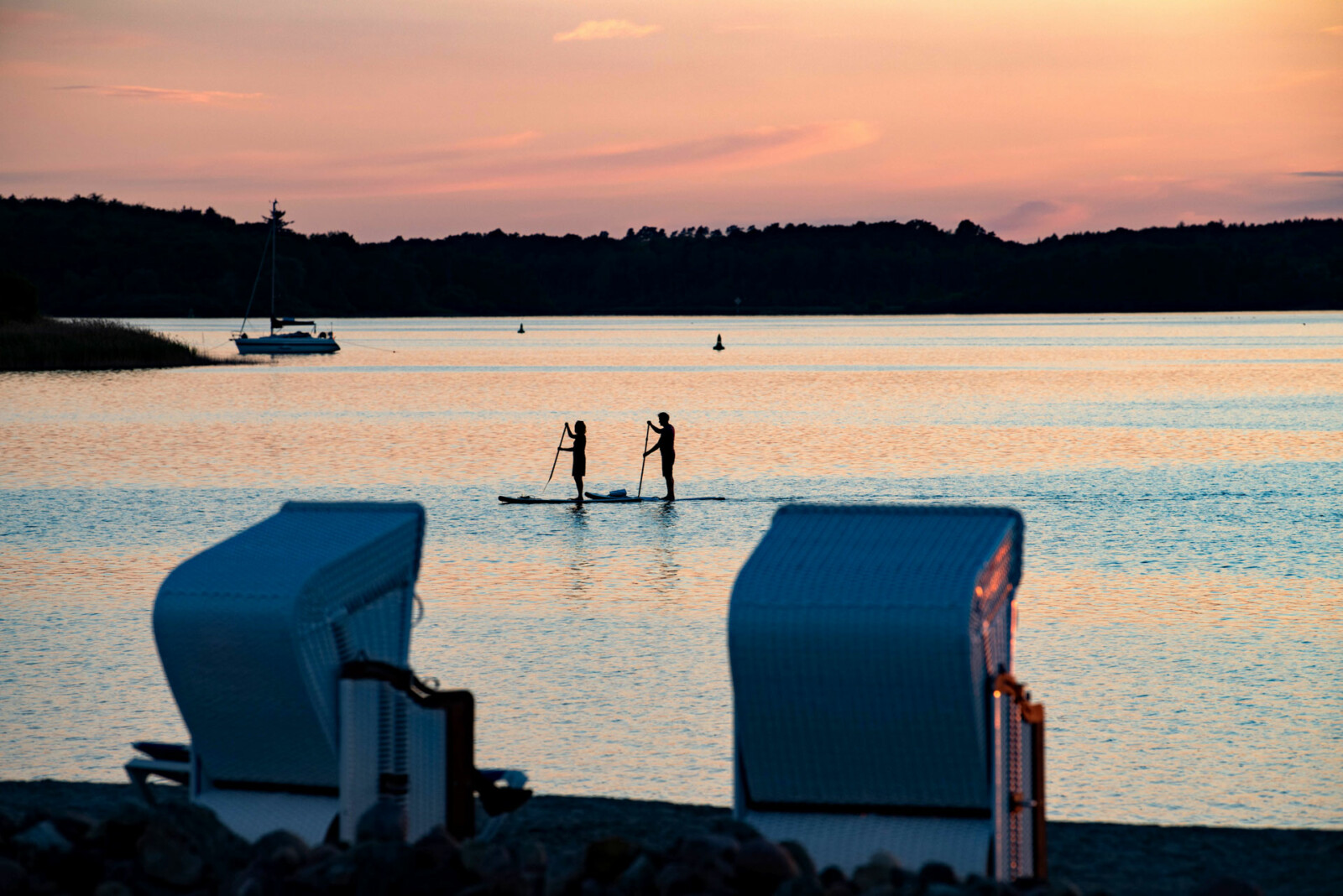 Sonnenuntergang über dem See mit SUP Paddlern.