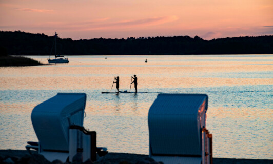 Sonnenuntergang über dem See mit SUP Paddlern.