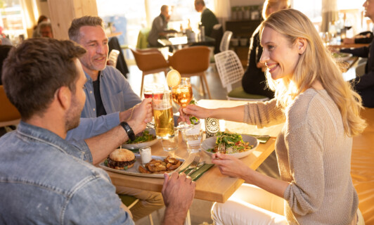 Drei Leute genießen Essen und Getränke im BellaRiva Restaurant.
