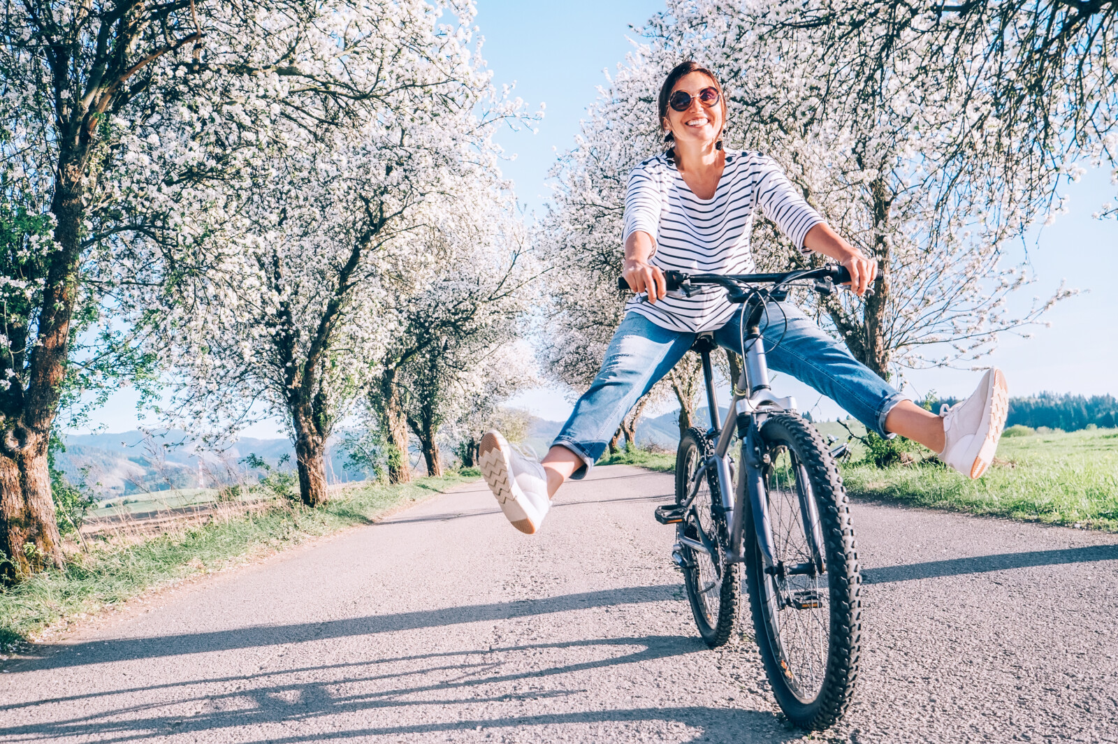 Eine Frau fährt Fahrrad auf einem Weg im Frühling.