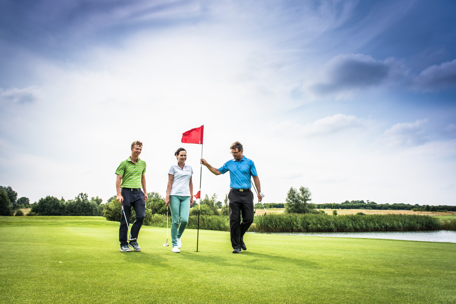 Drei Golfer auf Puttinggreen.