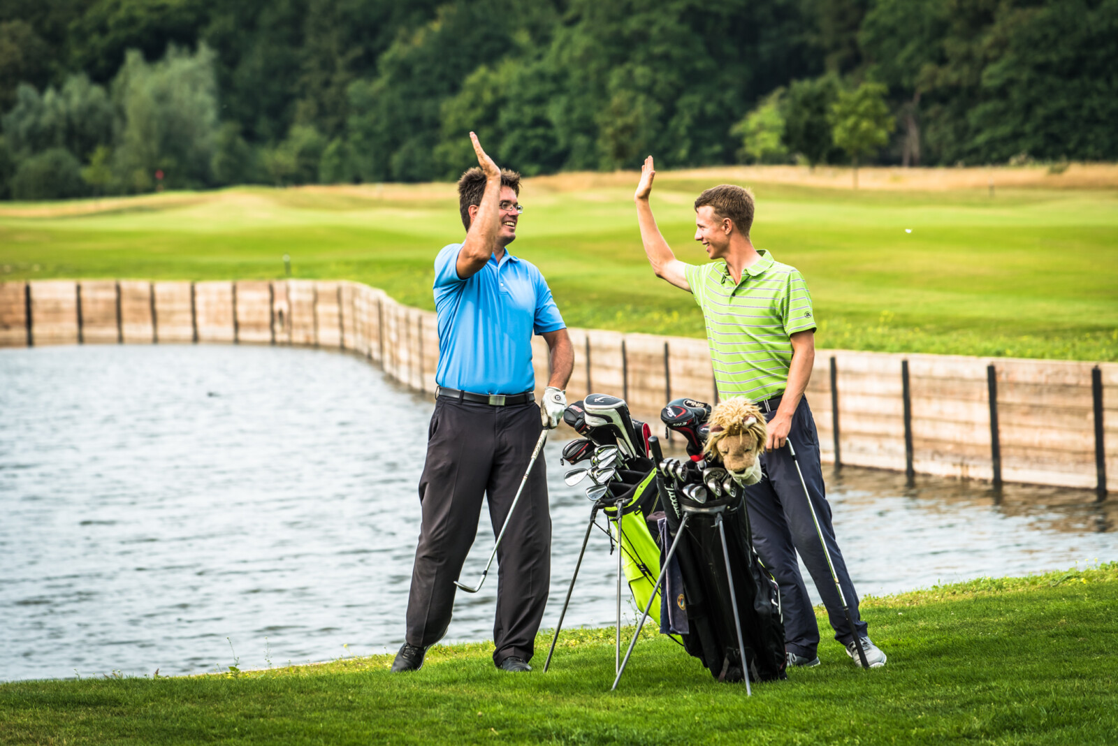 Golfer geben sich einen High-Five vor dem Teich auf dem Schloss Golfplatz.