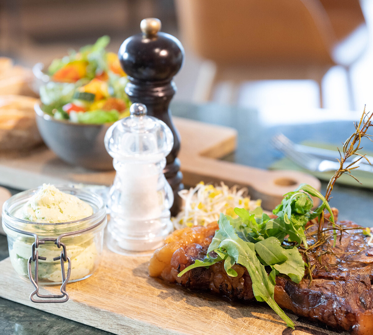Steak auf einem Holzbrett mit Salz und Pfeffer im BellaRiva Restaurant.
