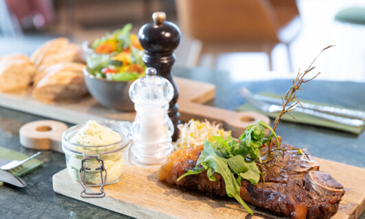 Steak auf einem Holzbrett mit Salz und Pfeffer im BellaRiva Restaurant.