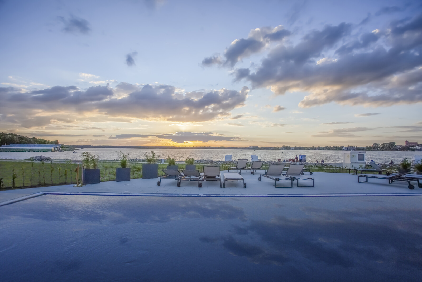 Sonnenuntergang auf der Terrasse mit Pool im MareMüritz mit Blick auf den See und Sonnenliegen.