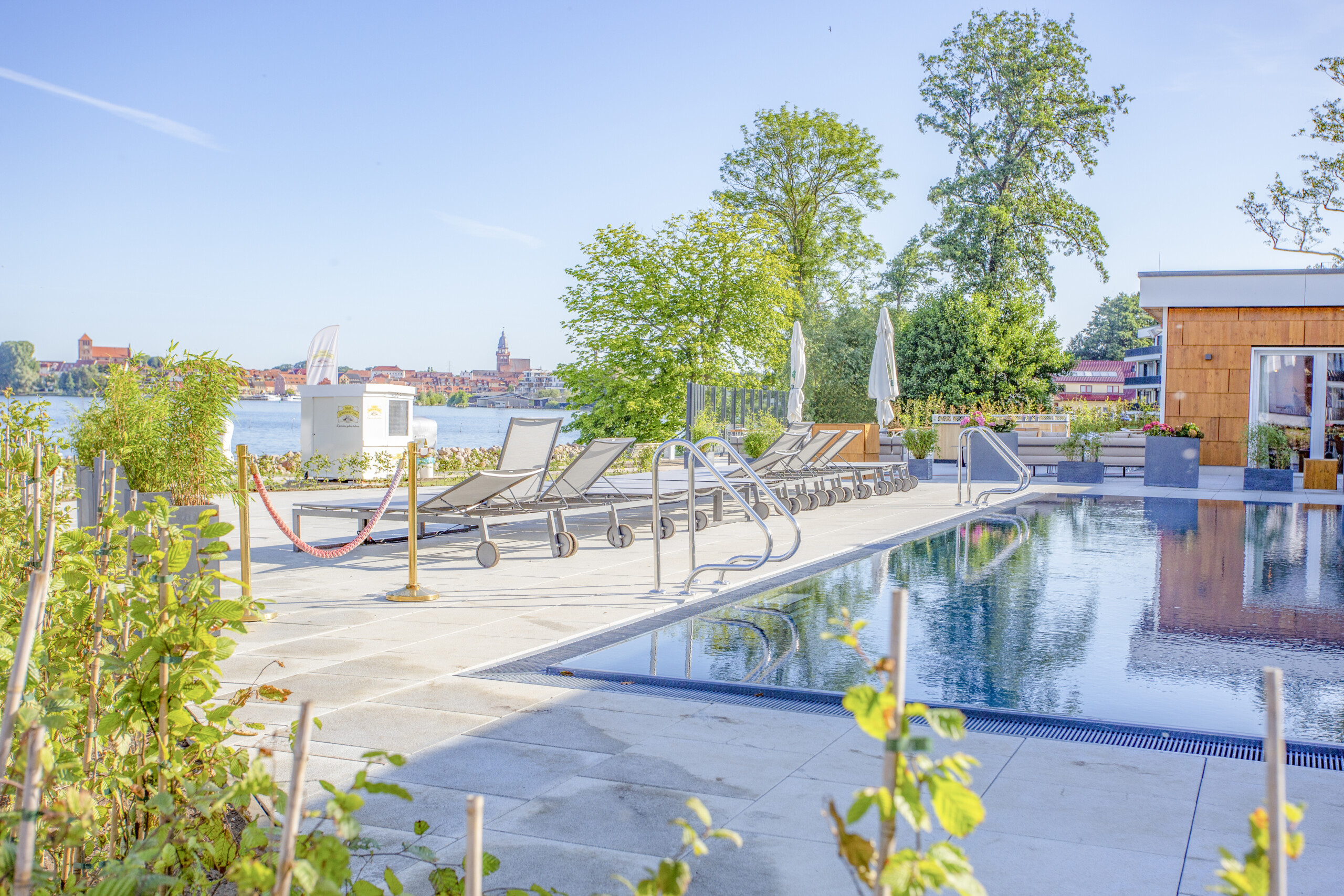 Außenpool und Sonnenliegen mit Blick auf Müritz bei Sonnenschein.