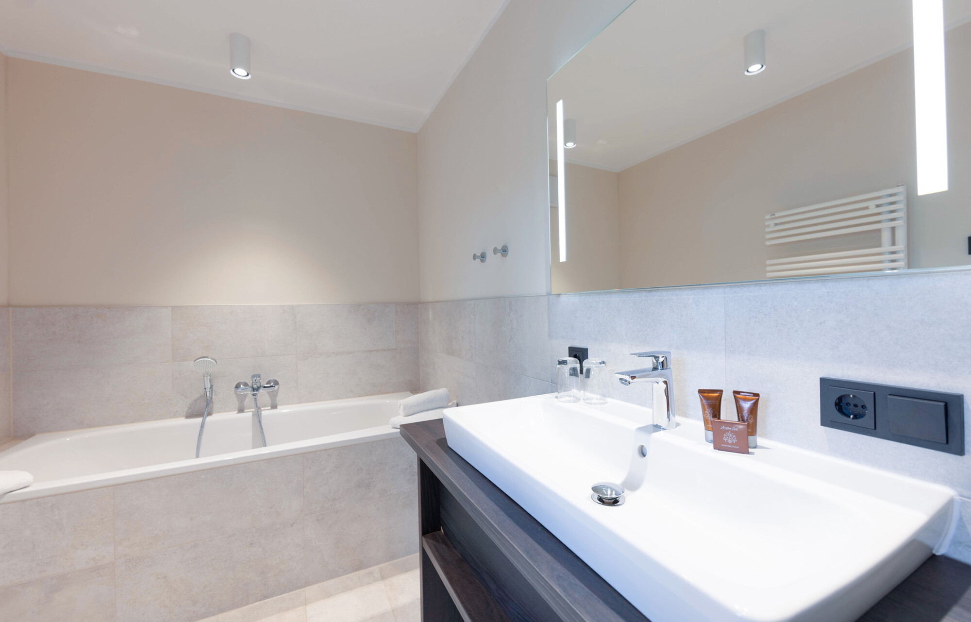 Helles Badezimmer mit Badewanne und Waschbecken in der Mare Grand Maisonette Suite.