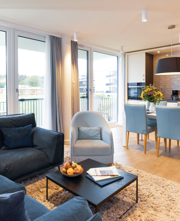 Gemütliches Sofa im Wohnbereich mit Esstisch und Küche in der Fortuna Suite.