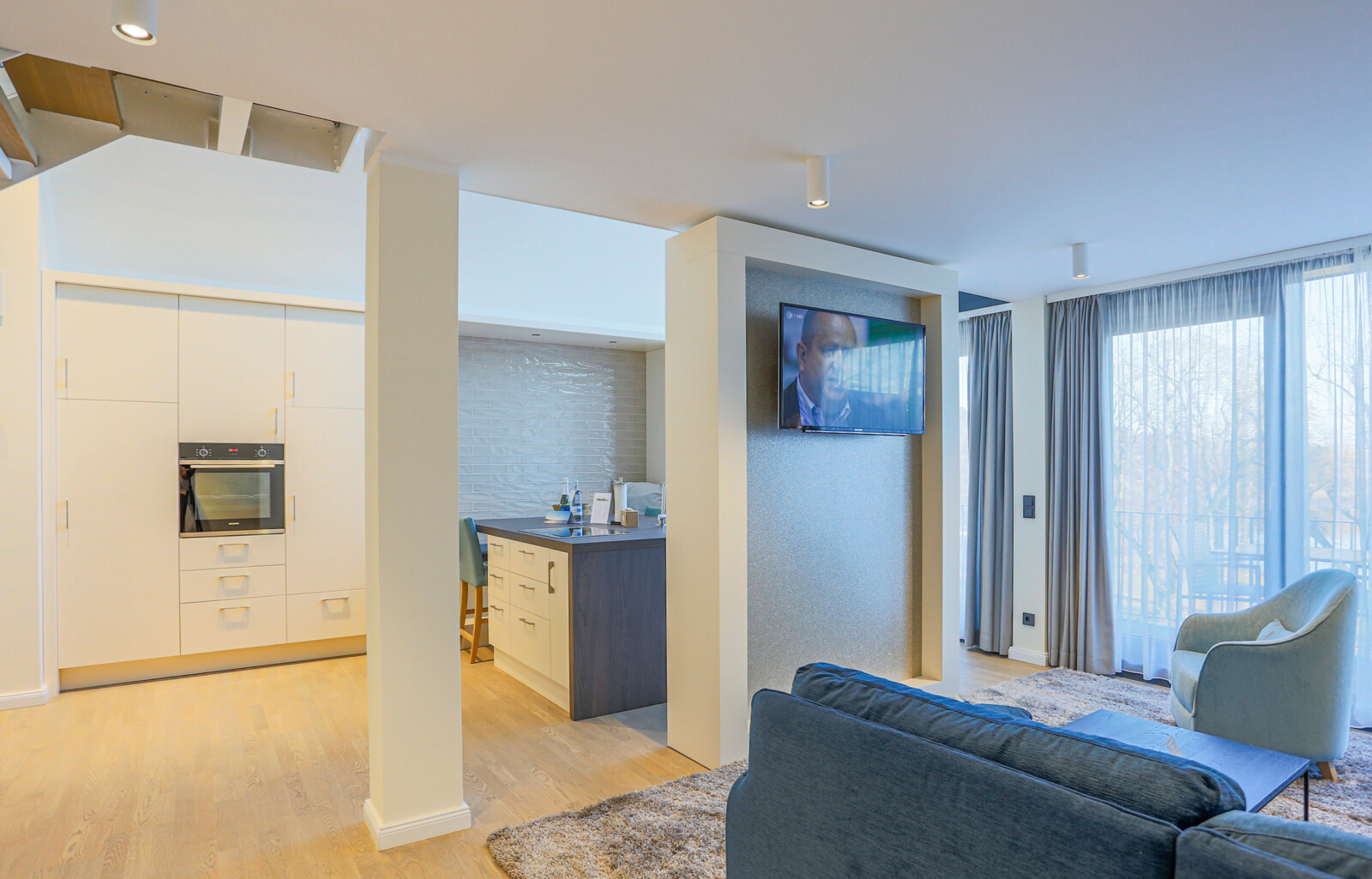 Wohnbereich mit Fernseher und Küche in der Kompass Maisonette Suite.