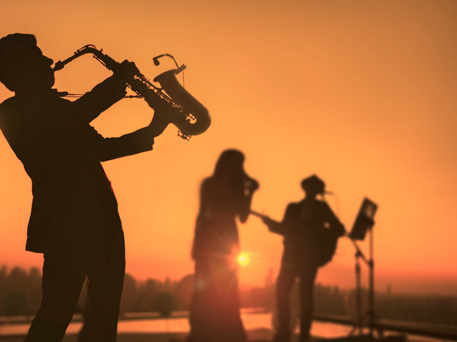 Drei Musiker vor einem Sonnenuntergang.