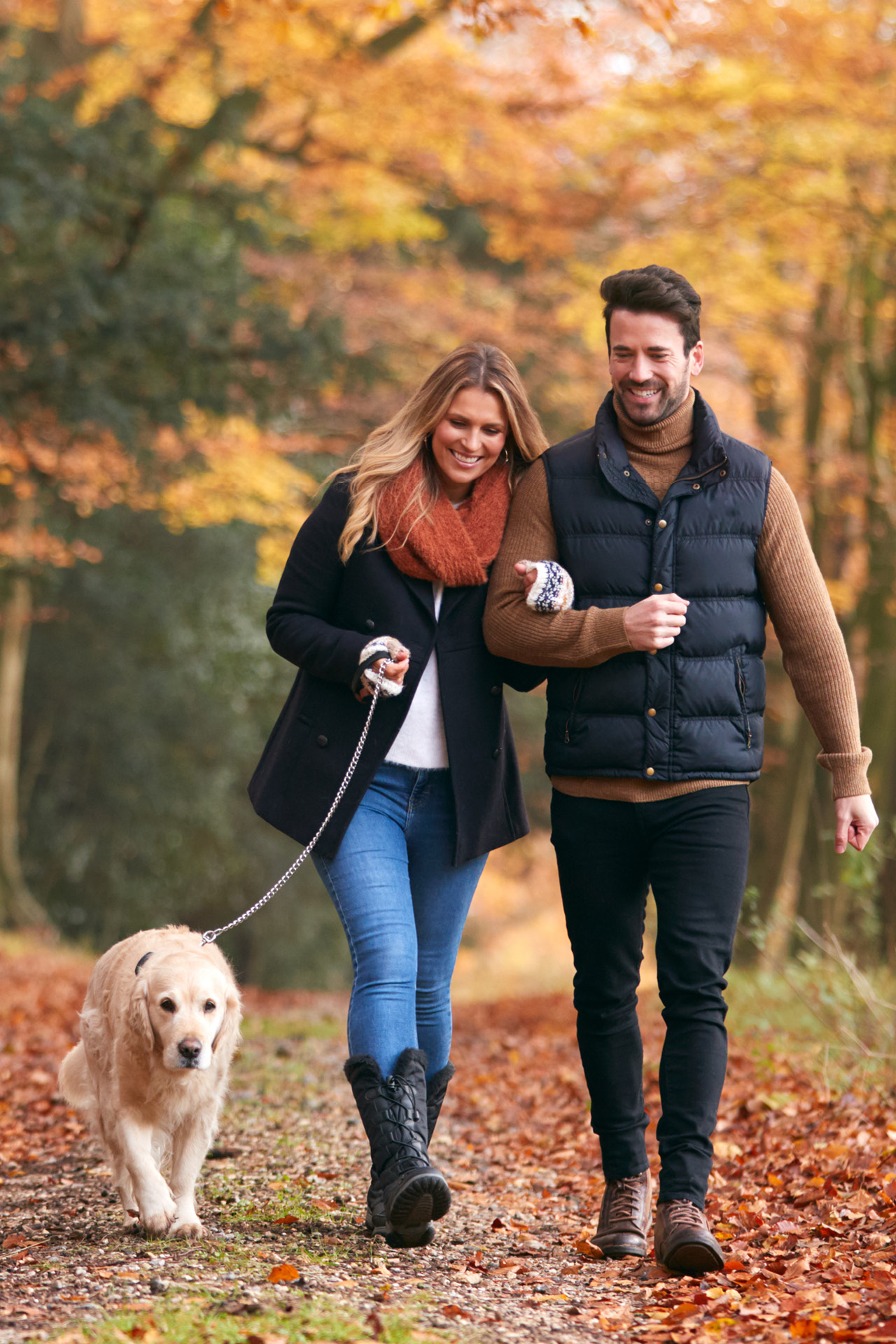Ein Paar geht mit dem Hund im Herbstwald spazieren.
