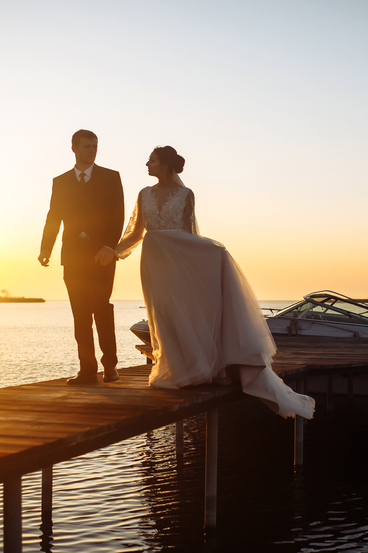Hochzeitspaar auf einem Steg im Sonnenuntergang im Yachthafen Resort Maremüritz.