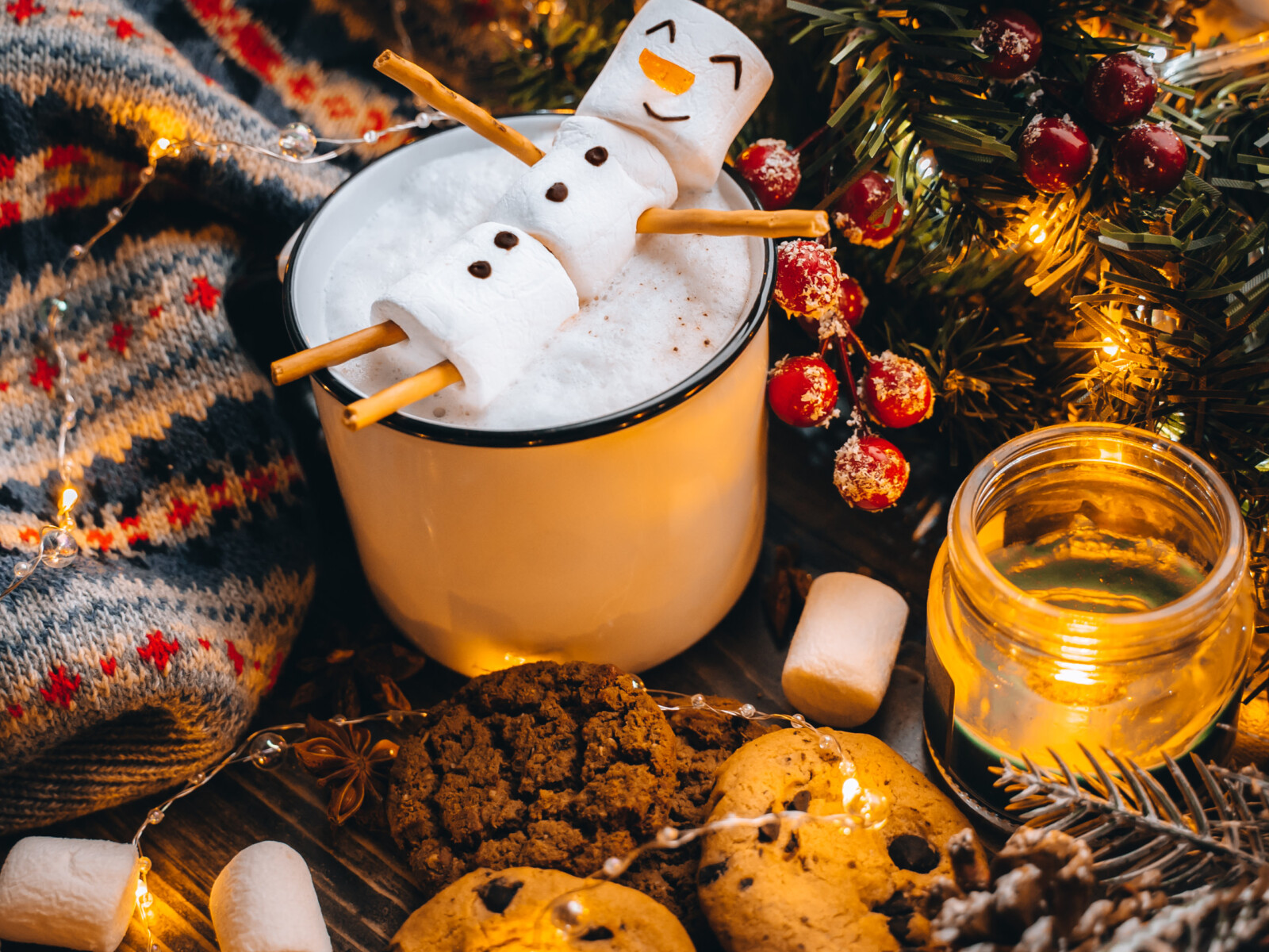 Weihnachtliche Süßigkeiten und eine heißte Schokolade mit einem Schneemann aus Marshmallows.