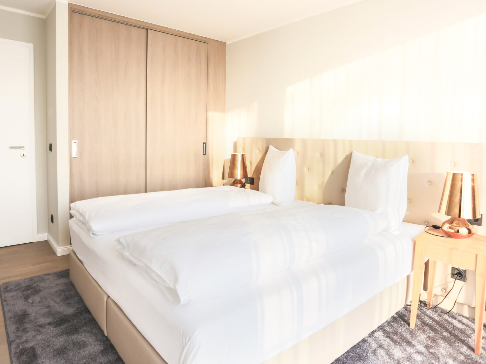 Beiges Bett auf grauem Teppich im Appartement im Maremüritz Yachthafen Resort.
