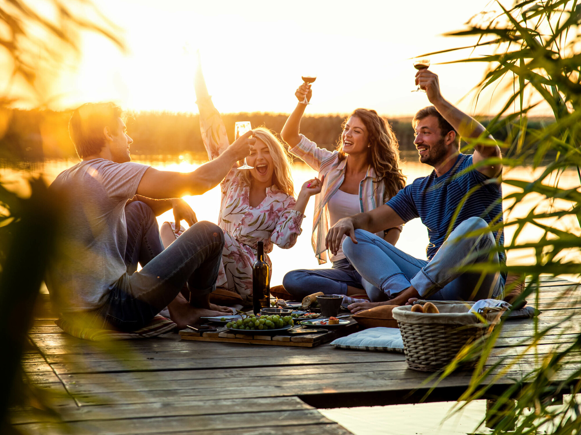Gruppe beim Picknicken auf einem Steg im Sonnenuntergang